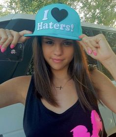 a girl wearing a hat with the word haters on it and holding her hair