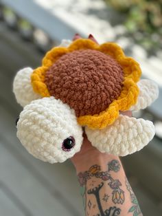 a hand holding a stuffed animal with a sunflower on it