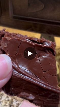 a person holding a piece of chocolate cake in their hand, with the video below it