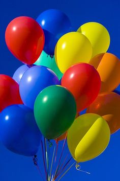 a bunch of balloons floating in the air on a sunny day with blue sky behind them