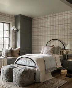 a bedroom with plaid wallpaper and bedding in the corner, along with two ottomans