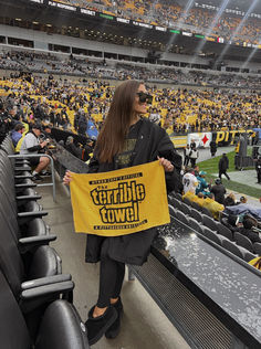 a woman is holding up a yellow banner in the stands at a football game,