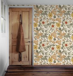 an open door in front of a floral wallpaper with flowers and leaves on it