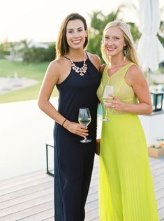 two women standing next to each other holding wine glasses