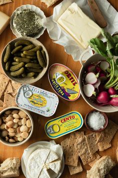 several different types of food are arranged on a wooden table with cheese, crackers and vegetables