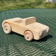 a wooden toy car sitting on top of a green table