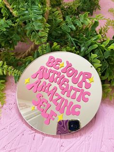 a mirror with the words be your authentic magic show on it next to some plants