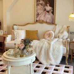 a living room filled with furniture next to a white table and chair in front of a painting on the wall