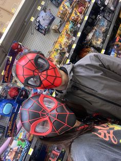 a person wearing red and black spider - man masks in a store with other items