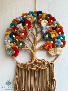 a tree with multi colored flowers hanging from it's roots on a white wall