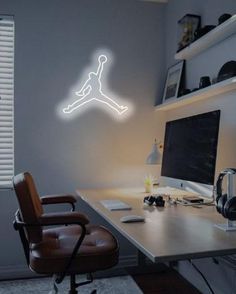 a desk with a computer and headphones on it in front of a wall mounted basketball player