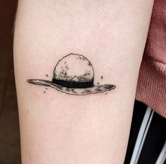 a small black and white hat tattoo on the right arm, with water droplets coming out of it