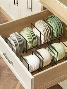 an open drawer with dishes in it and some cupboards full of plates on the bottom