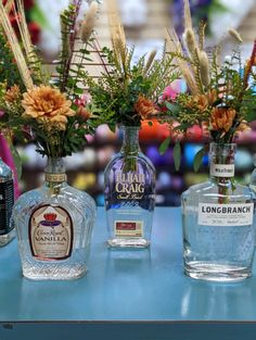 four bottles of liquor sitting on top of a table next to flowers and plants in vases