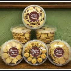 four plastic containers filled with cookies and chocolate chips on top of a wooden table next to a green wall