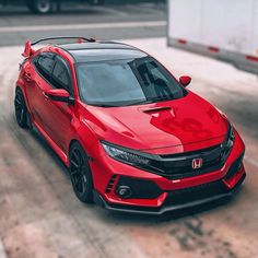 a red honda civic hatchback parked in a parking lot