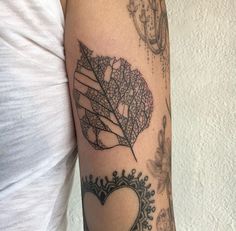 a woman's arm with a leaf and heart tattoo on the left side of her arm