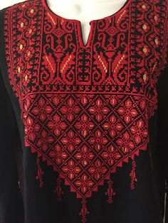 a black and red top with an intricate design on the chest, along with a white mannequin head