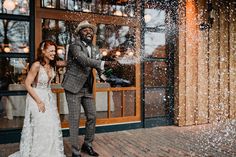 a bride and groom standing in front of a storefront with snow falling on them