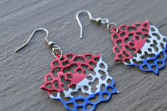 red, white and blue lace earrings on wooden surface with silver earwires hanging from them