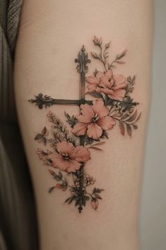 a cross with flowers on the side of her thigh is shown in this tattoo design