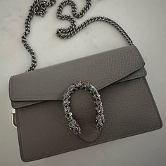 Up For A Sale Is A Pristine, Authentic Gucci Dionysus Super Mini. *Guaranteed Authentic, Poshmark Will Authenticate* Description: - Used Twice, Perfect Condition: No Scratches, Scuffs, Odor Free - Pet And Smoke Free Home - Color Is Discontinued: Gray - Tiger Head Spure Closure With Swarovski Crystals - Detachable Interior Key Ring - Palladium Toned Hardware - Moire Lining - Made In Italy - Approximate Measurements: 6.5” X 3.9” X 1.6” - 23.6” Shoulder Strap Drop Gucci Dionysus Super Mini, Tiger Head, Gucci Dionysus, Key Ring, Key Rings, House Colors, Mini Bag, Swarovski Crystals, Shoulder Strap