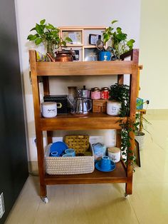 a shelf filled with pots and pans on top of a hard wood floor next to a wall