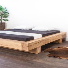 a bed sitting on top of a hard wood floor next to a potted plant