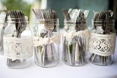 four mason jars with forks and spoons in them are lined up on a table