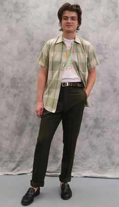 a young man standing in front of a wall wearing glasses and a shirt with an animal print on it