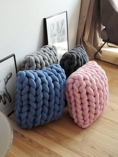 three different colored knitted pillows sitting on the floor next to pictures and framed photographs