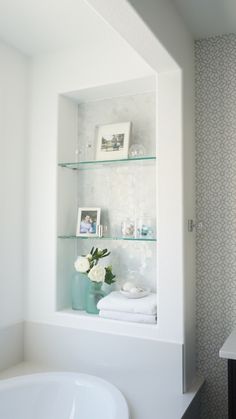 a bathroom shelf with flowers and pictures on it