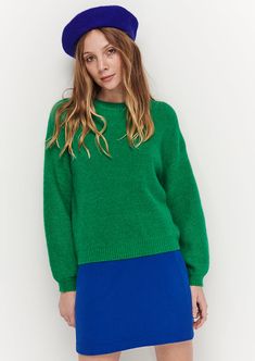 a woman wearing a green sweater and blue skirt