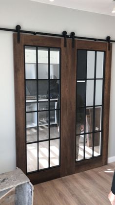 a person standing in front of two sliding glass doors with black hardware on the top and bottom