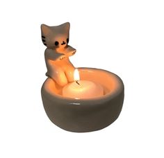 a cat sitting in a bowl with a lit candle