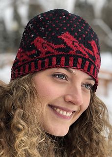 a smiling woman wearing a red and black knitted hat with snow flakes on it