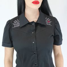 To all Rockabilly fans and those in love with the spooky genre, this lavish top is now available for you to style! The cute collar, short sleeves, and snaps make the blouse oh so girly and stylish.  Dress up with high waist pants or fitted jeans, circle skirts, and rockabilly pumps or flats. - Machine Washable - 100% Cotton - Made in USA Measurements are in inches SizesBust....Waist....Length X-Small322826 Small343026 Medium....363227 Large383428 X-Large403629 2XL423829 3XL444030 Gothic Fitted Short Sleeve Top, Fitted Gothic Short Sleeve Tops, Fitted Black Blouse For Halloween, Fitted Short Sleeve Alternative Tops, Fitted Alternative Style Top With Short Sleeves, Punk Style Short Sleeve Halloween Tops, Edgy Short Sleeve Halloween Tops, Rocker Fitted Tops For Halloween, Rocker Style Fitted Tops For Halloween