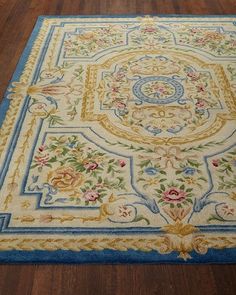 a blue and yellow rug on the floor with wooden floors in front of it,