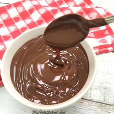 a spoon in a bowl filled with chocolate sauce on top of a red and white checkered napkin