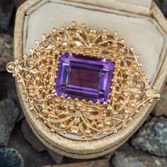 This gorgeous amethyst pendant brooch is centered with an emerald cut amethyst in the center of a navette shape of gold open filigree work. The jewel is meant to be worn North-to-South as a pendant and East-to-West as a brooch. The pin is off to the side and does not show when being worn as a pendant. It is crafted in 14k yellow gold and is approximately 1.75" long. The chain in the photo is not included. Elegant Purple Gemstone Brooches, Purple Brooch Jewelry For Evening, Purple Amethyst Gemstone Brooches, Purple Gemstone Brooches For Gift, Elegant Amethyst Brooches For Wedding, Elegant Purple Amethyst Ring With Filigree, Amethyst Brooch Jewelry Gift, Elegant Purple Amethyst Filigree Ring, Purple Amethyst Brooches For Wedding