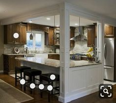 an open concept kitchen and living room with lights on the countertop, along with bar stools