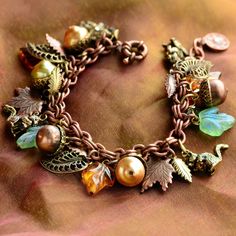 "Sure to be a favorite autumn keepsake! Three hungry little squirrels are hiding among the charms of our fall harvest bracelet of pearl acorns, art glass leaves and leaves of different trees in copper and bronze. The double rolo link bracelet is fastened by a byzantine clasp. Warm and whimsical yet sophisticated and timeless. Adjustable up to 8\" length (20cm). You may specify a custom length. Made at Sweet Romance in our Los Angeles studio. To see coordinating necklace, click this link: https:/ Squirrel Jewelry, Bracelet Displays, Squirrel Necklace, Jingle Jangle, Autumn Bracelet, Autumn Necklace, Retail Jewelry, Fall Inspiration, Leaf Bracelet