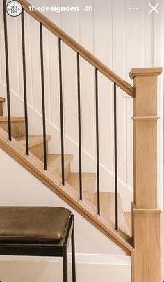 a wooden stair case next to a black bench