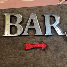 the word bar is made up of metal letters and an arrow pointing to the right