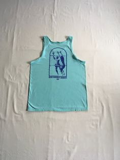 "vintage 1990s tank top shirt Hanes Beefy T 100% cotton, made in USA single stitch sea foam green w/image on back- front of shirt is blank back- print of 2 men playing volleyball (1 on each side of net w/ball in air) writing- Beva Summer Doubles 1991 good vintage condition, light wear-light stain- see photos label size L, see below measures, lying flat, shoulder-12\" chest-20\" length-28\"" 90s Sports T-shirt For Summer, Summer Streetwear Crew Neck Tank Top, Cotton Gym T-shirt For Summer, Summer Muscle Tee For Gym, Summer Graphic Print Racerback T-shirt, Green Graphic Print Sleeveless Tank Top, Casual Summer Gym Tank Top, Blue Graphic Print Muscle Tee, Blue Casual Muscle Tee With Graphic Print