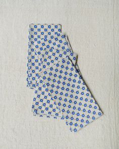 a blue and white flowered tie laying on top of a tablecloth covered floor