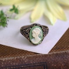 Oxidized silver or antiqued brass ring which is adjustable in size and has oak leaf details on the sides.  In the center is a 14x10mm green and white girl cameo. Victorian Green Cameo Jewelry, Antique Green Cameo Jewelry, Vintage Adjustable Cameo Rings, Vintage Adjustable Cameo Jewelry, Adjustable Vintage Green Rings, Green Vintage Adjustable Rings, Vintage Green Nickel-free Rings, Dr Jewelry, Thinking Thoughts