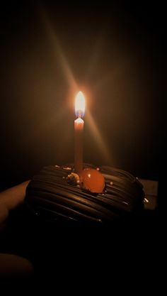 a lit candle sitting on top of a chocolate cake