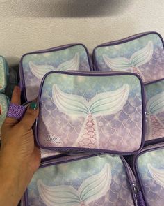 four mermaid themed lunch bags with one being held up to the side by someone's hand