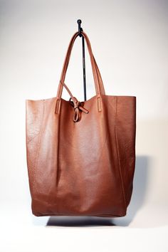 A lightweight and spacious Leather Shopper Bag-Tan you can use for your office, gym and after-hours essentials while still looking stylish. Handmade from supple calfskin Italian leather, the versatile look features over-the-shoulder handles and minimal detailing. Raw edges and no lining makes this style super light and easy to fold when traveling. Inside is a zippered document pouch and a leather cell phone pouch. Details: Color: TanTwo leather strap for closing the bag.Natural unlined interiorM Brown Smooth Grain Hobo Bag For Shopping, Everyday Textured Leather Cognac Hobo Bag, Cognac Textured Leather Hobo Bag For Everyday, Everyday Cognac Textured Leather Hobo Bag, Minimalist Brown Hobo Bag For Everyday, Everyday Casual Shoulder Bag With Smooth Grain, Leather Minimalist Hobo Bag For Daily Use, Minimalist Brown Hobo Bag For Daily Use, Minimalist Brown Bag With Smooth Grain